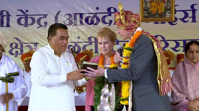 Penatua D. Todd Christofferson dari Kuorum Dua Belas Rasul bersama istrinya, Sister Kathy Christofferson, memberikan sebuah salinan Kitab Mormon kepada Presiden World Peace University Dr. Vishwanath D. Karad di Pune, India, 14 Agustus 2017.