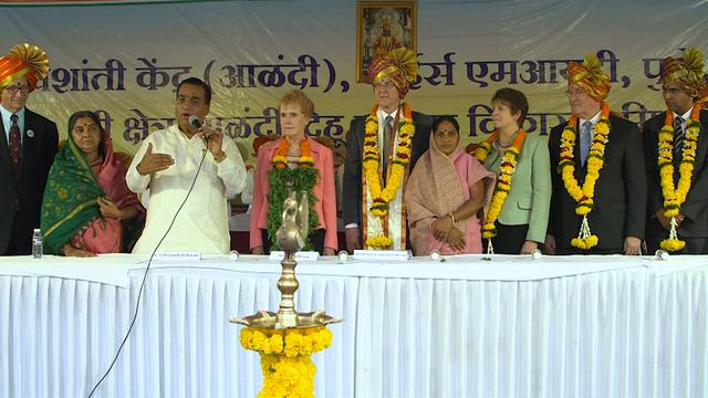 Presiden World Peace University Dr. Vishwanath D. Karad, berdiri di sisi Sister Kathy Christofferson dan Penatua D. Todd Christofferson dari Kuorum Dua Belas Rasul, bersama dengan para pemimpin lainnya, berbicara di acara penghargaan yang menghormati Gereja Yesus Kristus dari Orang-Orang Suci Zaman Akhir atas layanan kemanusiaan globalnya di Pune, India, 14 Agustus 2017.
